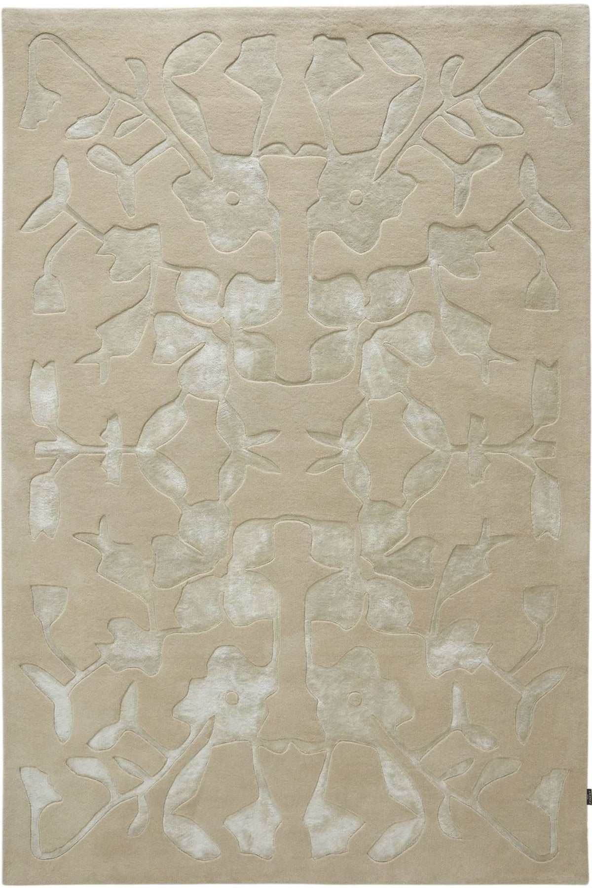 A rectangular area rug in a light beige or cream tone with a raised, abstract floral or leafy pattern in a slightly lighter off-white shade.
