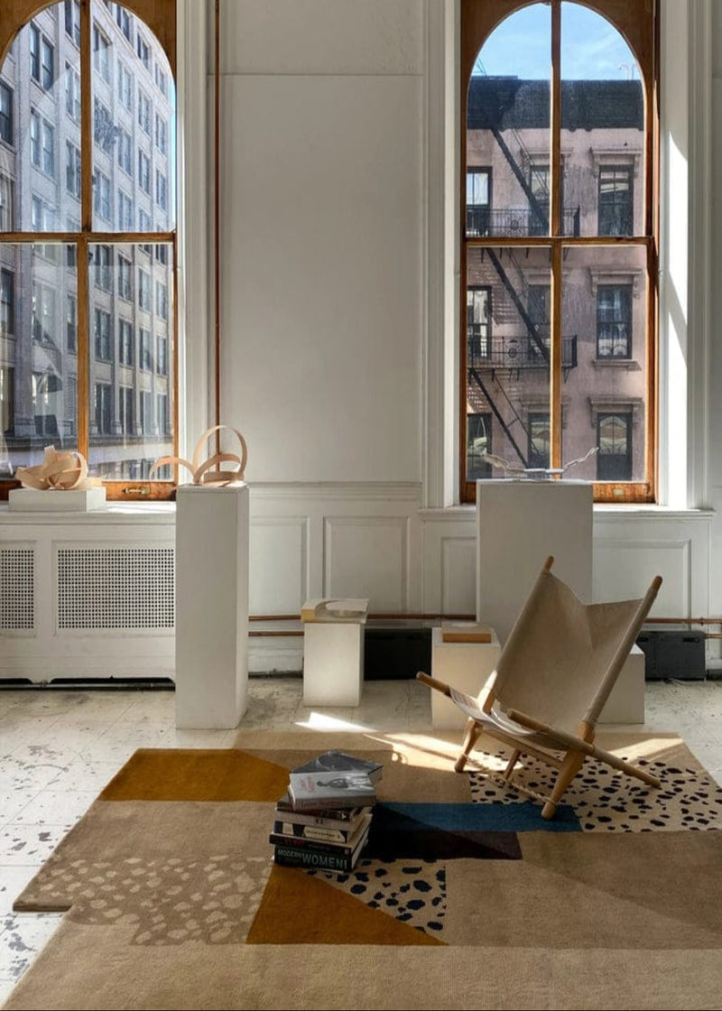 Modern interior with a chair, rug, and large windows. |NORDIC RUG | KALEENVIBE 