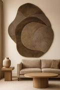 Modern living room with a large abstract wall sculpture, beige sofa, and wooden coffee table.