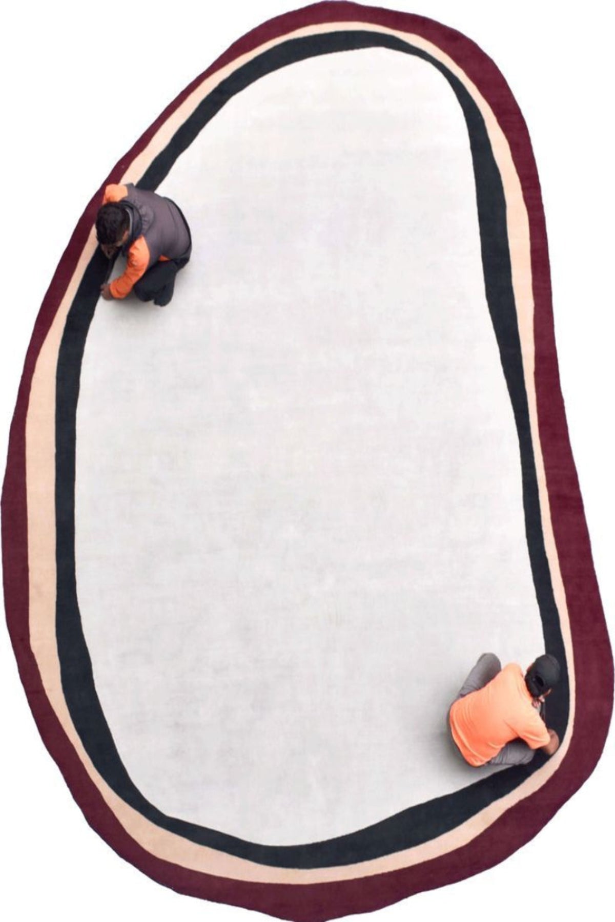 Oval-shaped mat with maroon border and two small orange objects on a white background